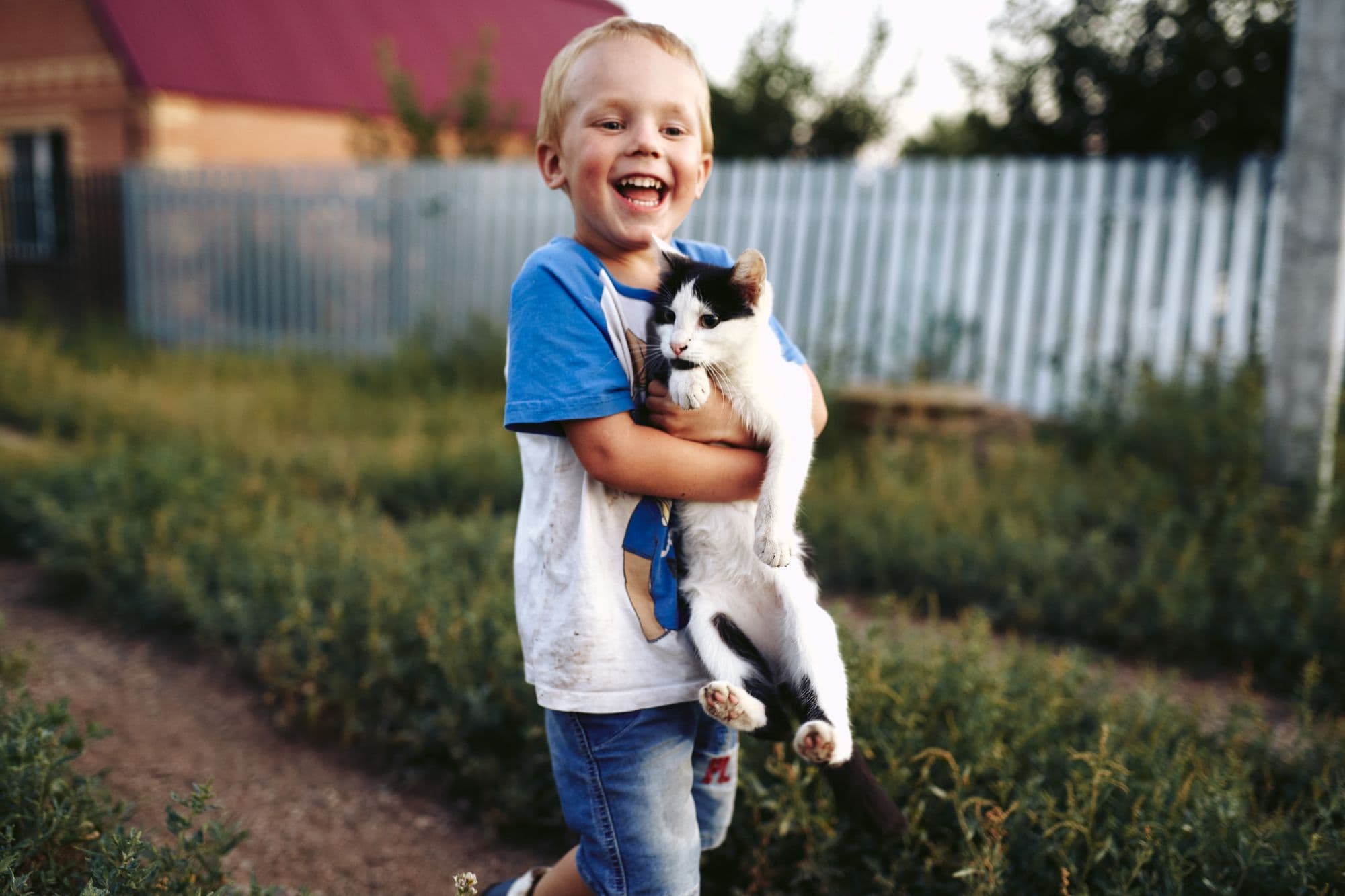 A smiling boy carrying his cat outside