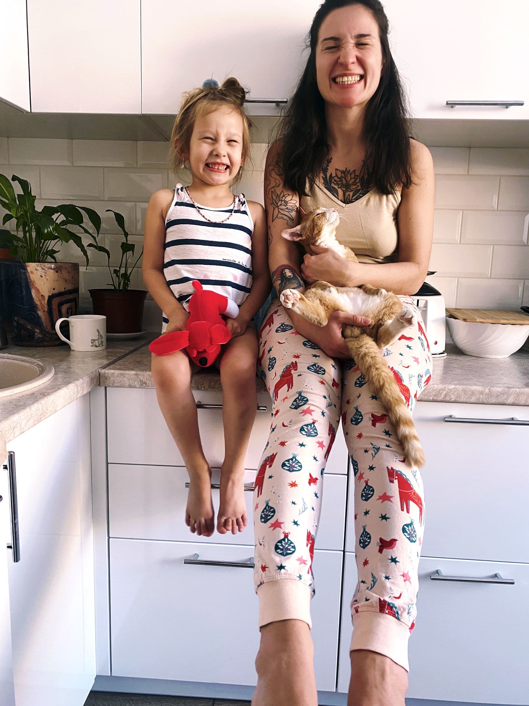 A mother and daughter sitting in the kitchen with their cat