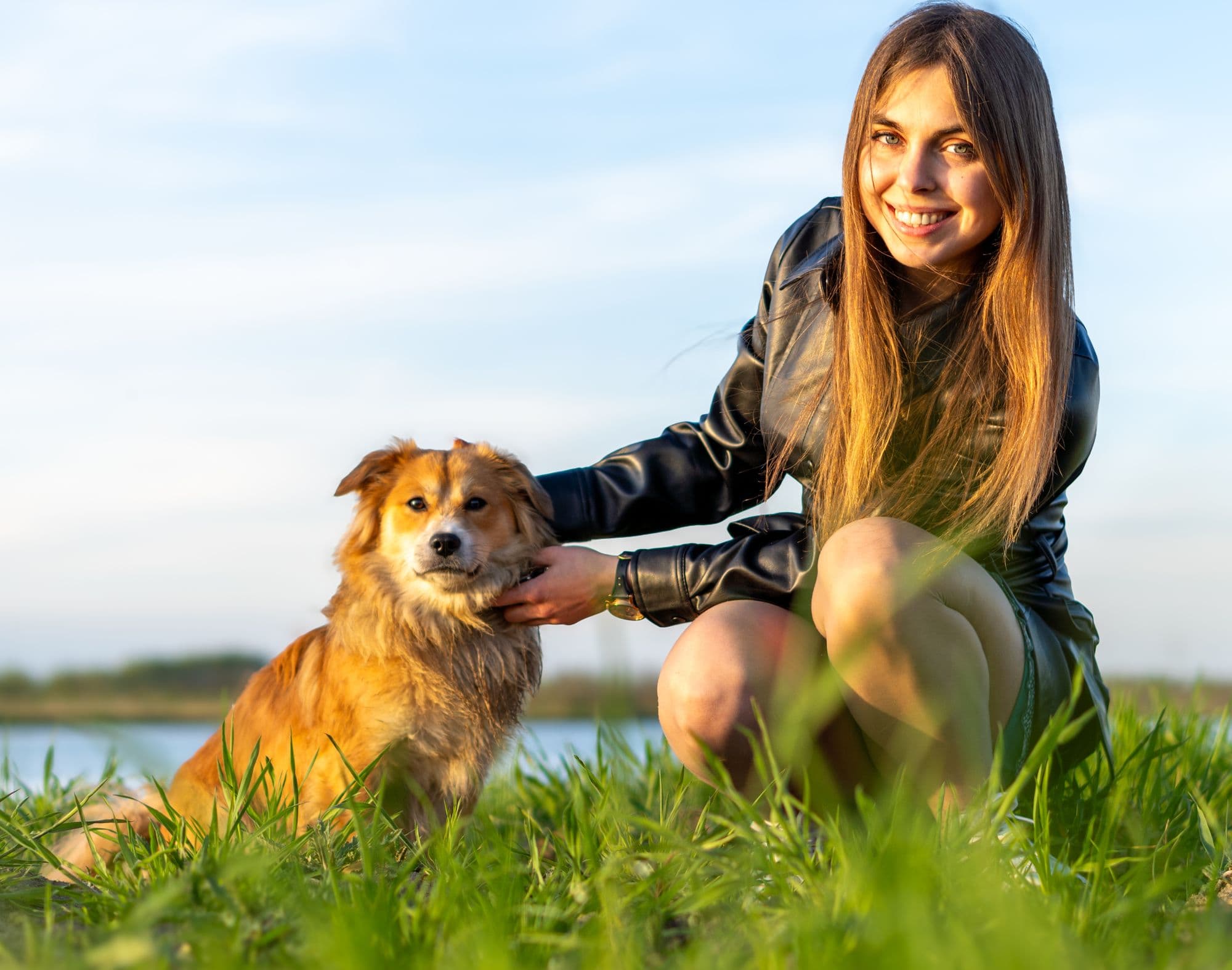 A smiling woman with her dog by a lake