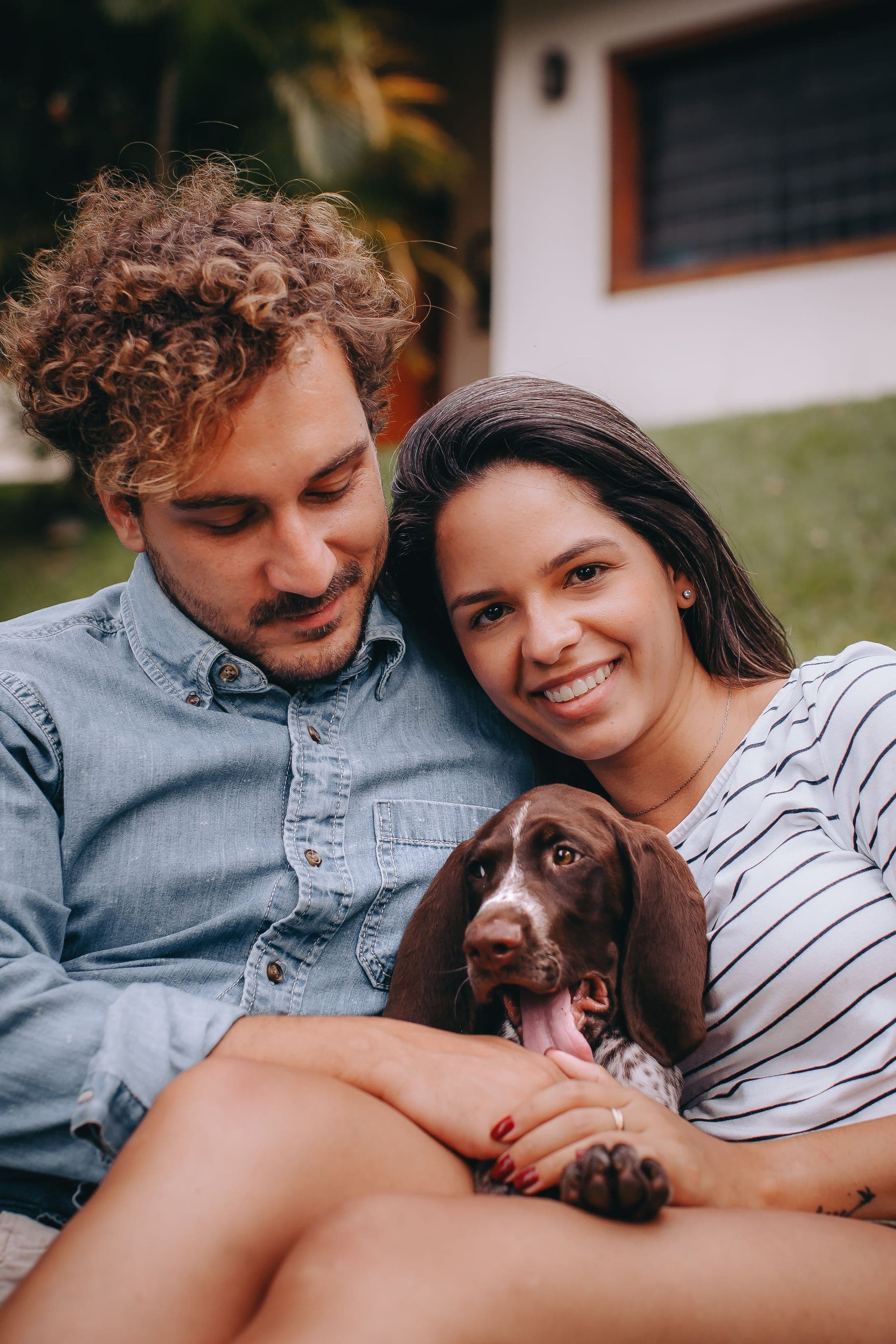 A smiling couple cuddling their spaniel puppy outdoors